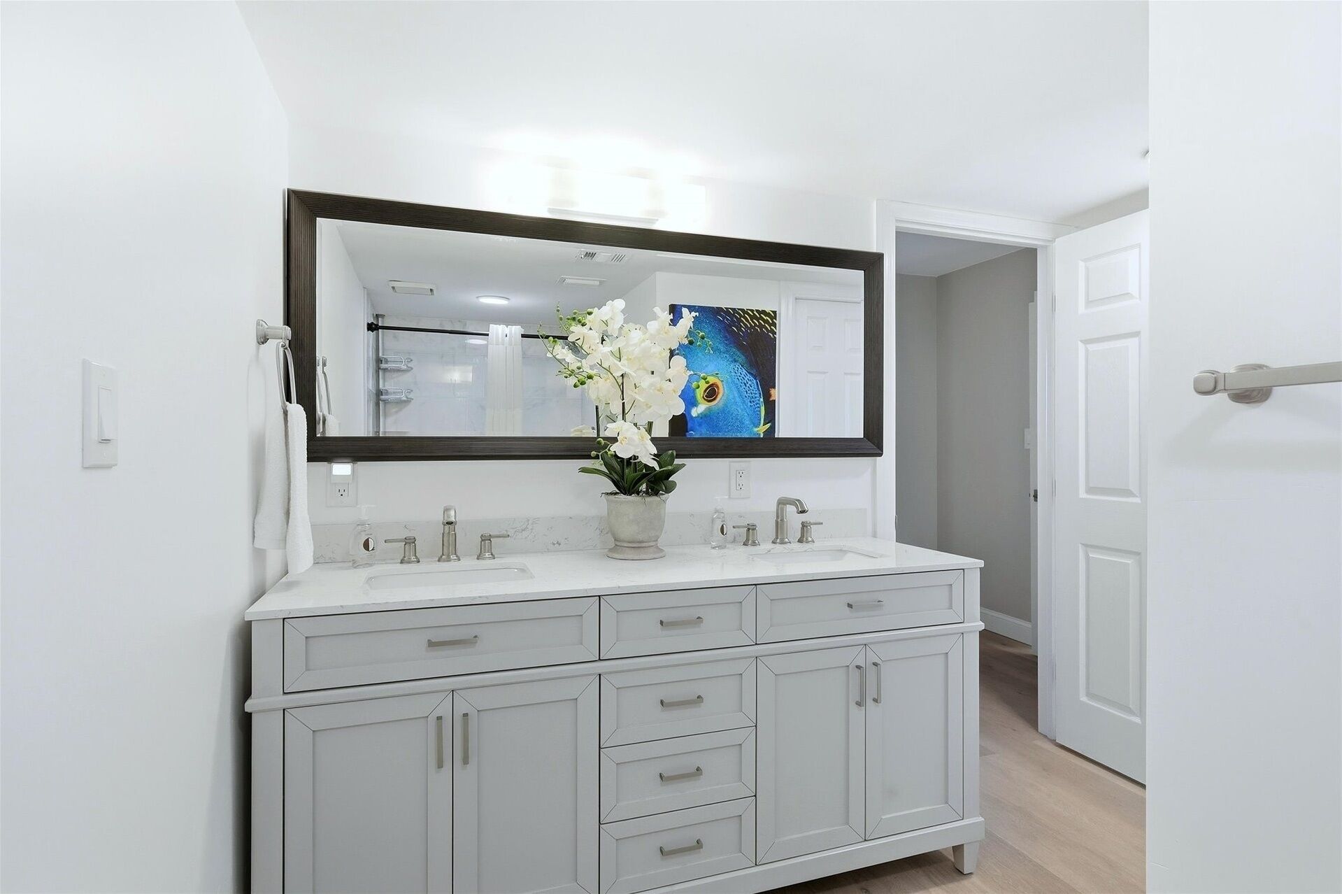 A bathroom with a white vanity, a large mirror, and a shower area.