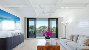Een moderne woonkamer met een bank, een salontafel, een televisie en een balkon met uitzicht.