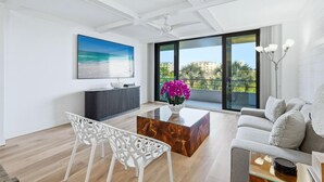Een moderne woonkamer met een grote televisie, een salontafel, een bank en een balkon met uitzicht.