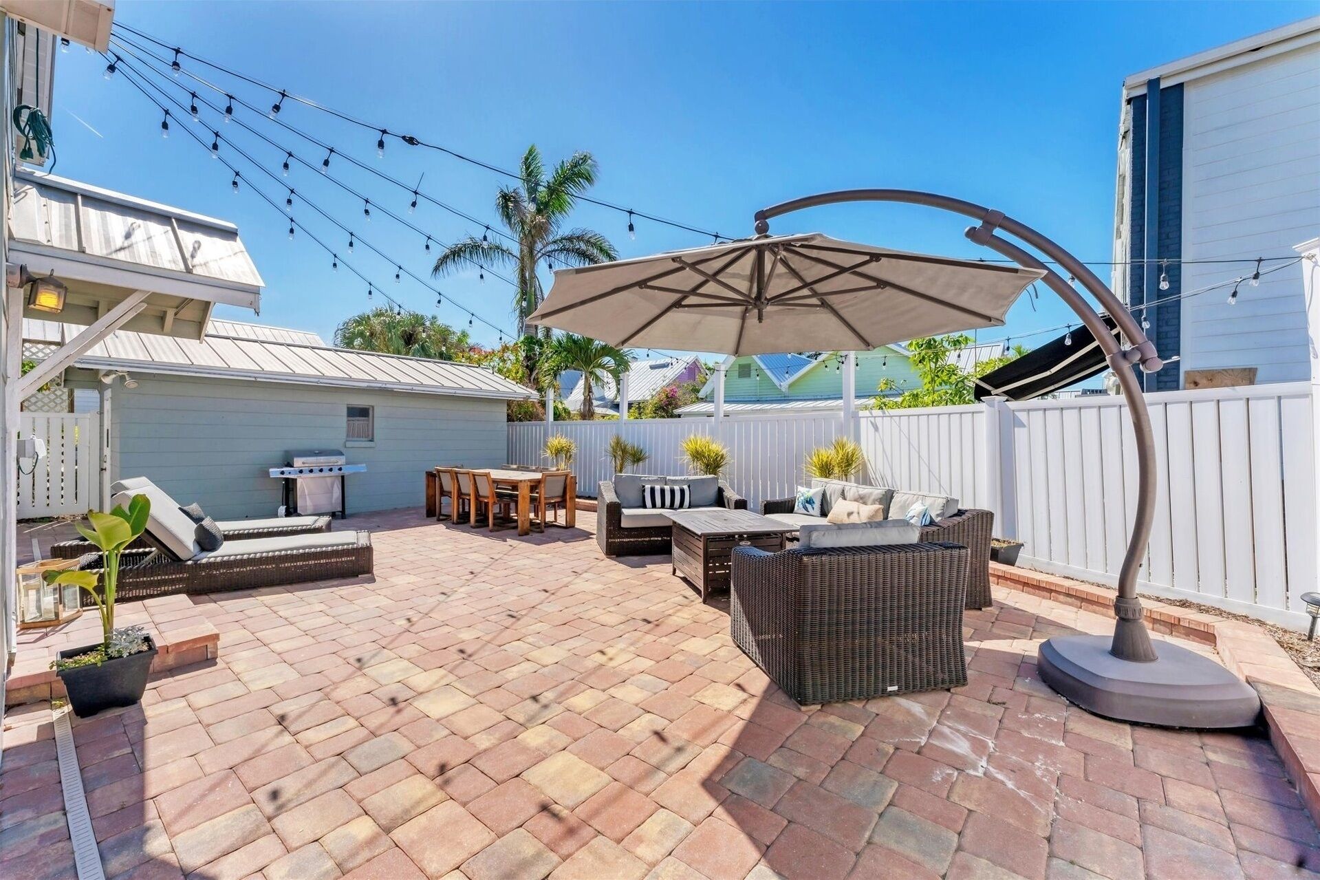 A patio with outdoor furniture, a barbecue grill, and string lights.