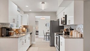 A modern kitchen with white cabinetry, granite countertops, and stainless steel appliances. - Cape Coral 3 Bedroom Private Pool Home - Canal Access 3 Home (Cape Coral)