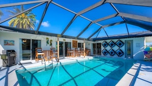 A covered pool area with a glass ceiling, poolside chairs, and a bar area. - Cape Coral 3 Bedroom Private Pool Home - Canal Access 3 Home (Cape Coral)
