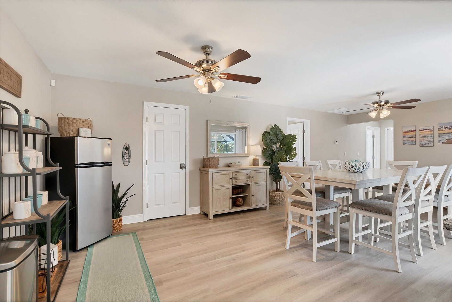 A spacious kitchen with a dining area, featuring a refrigerator, cabinets, and a dining table with chairs.