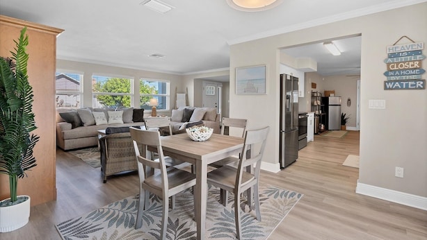 A modern kitchen with a dining area, a refrigerator, and a dining table with chairs. - Cape Coral 3 Bedroom Private Pool Home - Canal Access 3 Home (Cape Coral)