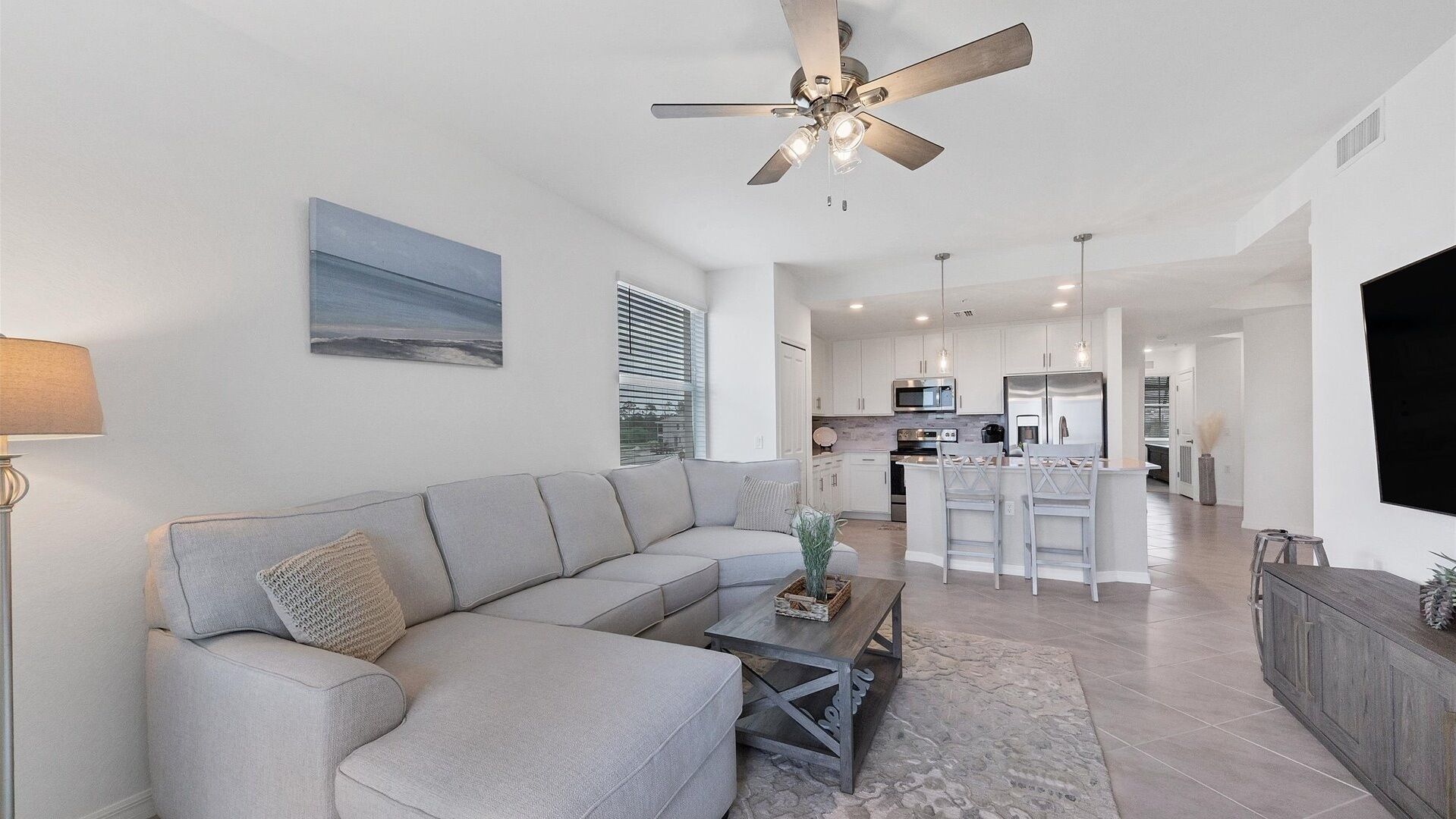 A modern living room with a sectional sofa, a coffee table, and a ceiling fan.
