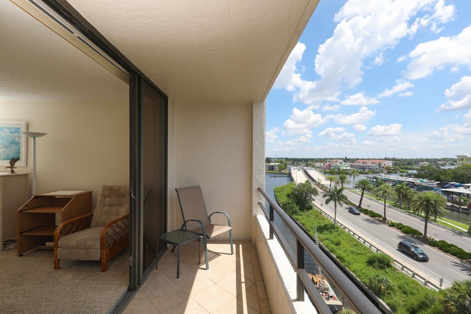 A balcony with two chairs, a small table, and a view of a river and cityscape.