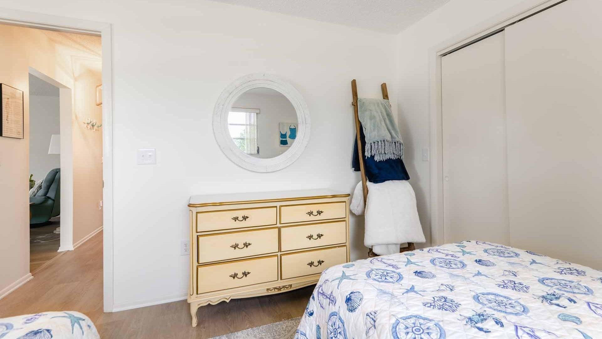 A bedroom with a bed, a dresser, a mirror, and a wardrobe.