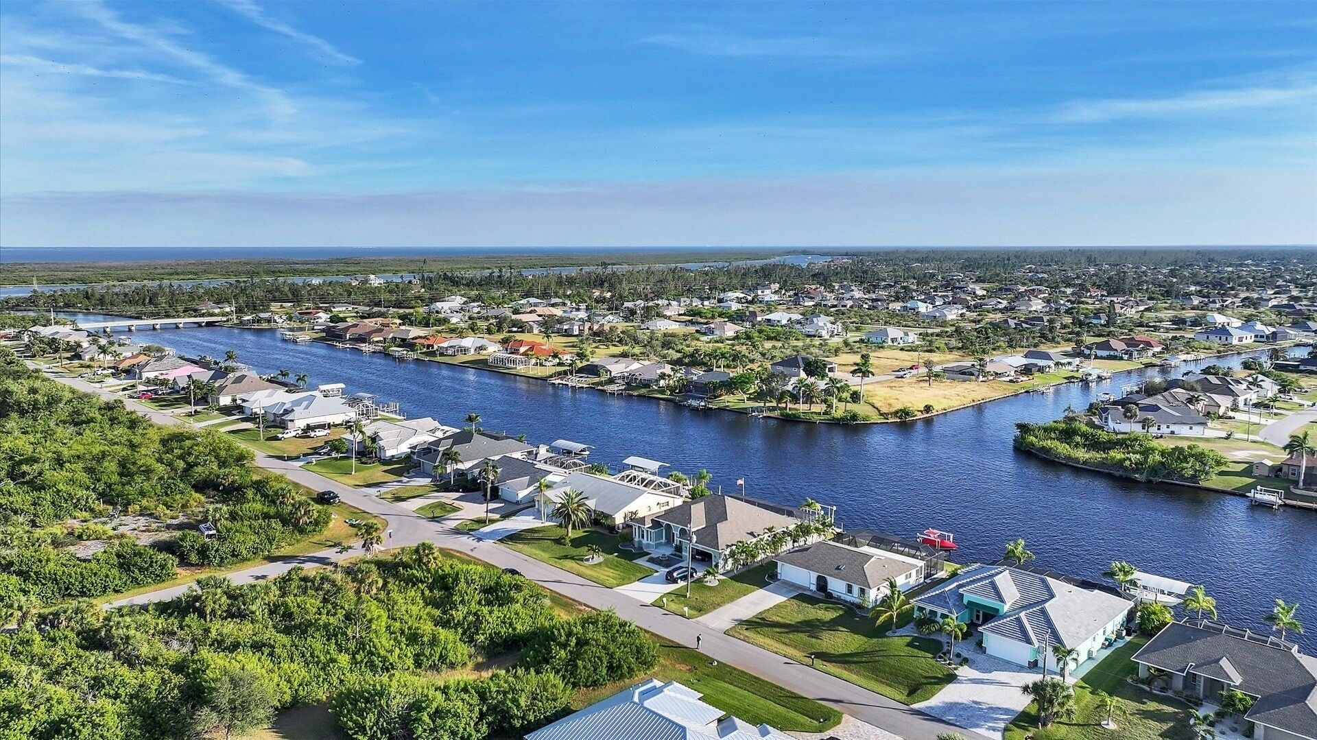 A residential area with houses along a river, featuring a bridge and a mix of single and multi-story buildings.