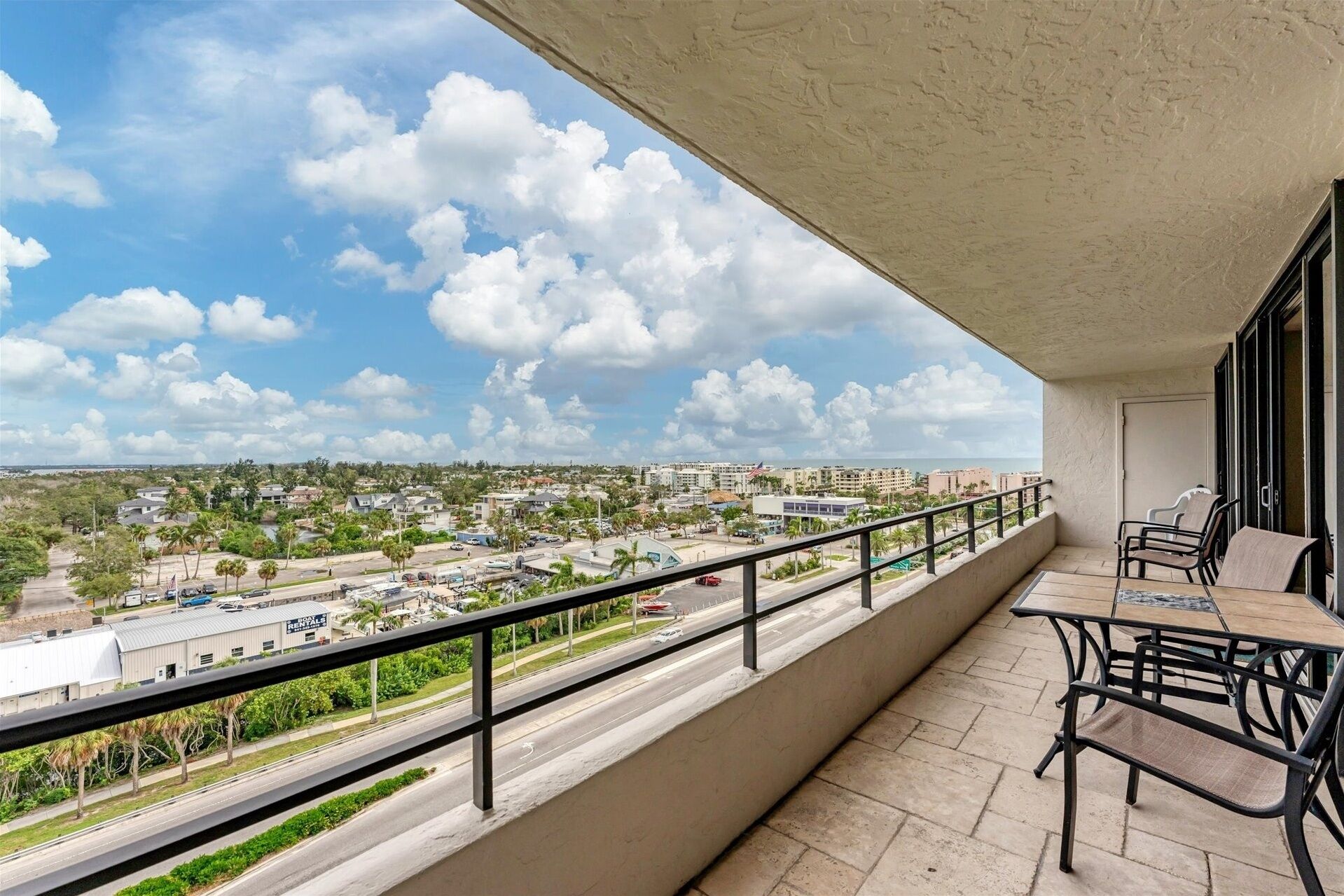 A balcony with a view of a cityscape, including buildings and a road.