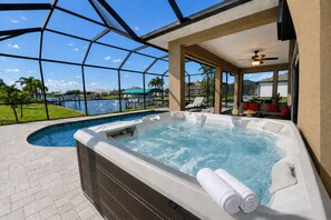 A hot tub with a view of a swimming pool and a patio area with outdoor furniture. - South Gulf Cove 3 Bedroom Canal Pool Home 3 Home (Port Charlotte)