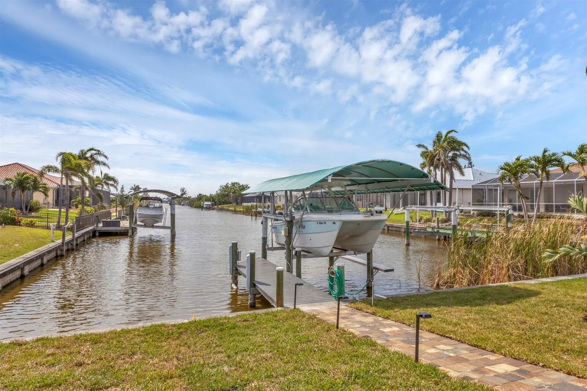 A canal with boats docked, a covered boat launch, and a pathway alongside the water.