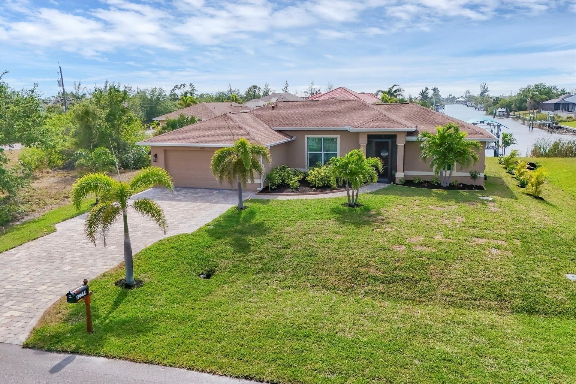 A single-story house with a tiled roof, a front porch, and a well-maintained lawn with palm trees.