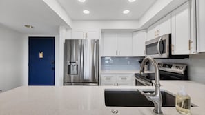A modern kitchen with white cabinets, stainless steel appliances, a water dispenser, and a sink with a soap dispenser. - Anchorage Resort Siesta Key 2 Bedroom 6th Floor Condo Beach Access 2 Condo (Siesta Key)
