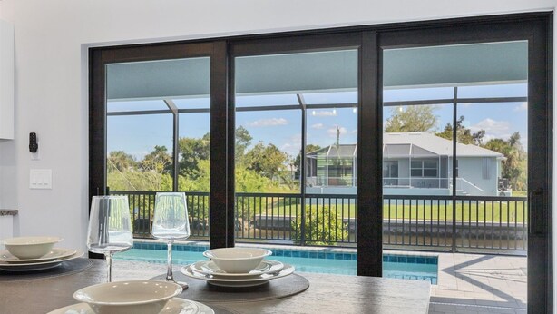 A dining area with a view of a swimming pool and a house. - Punta Gorda 4-Bedroom Private Pool Home on Canal 4 Home (Punta Gorda)