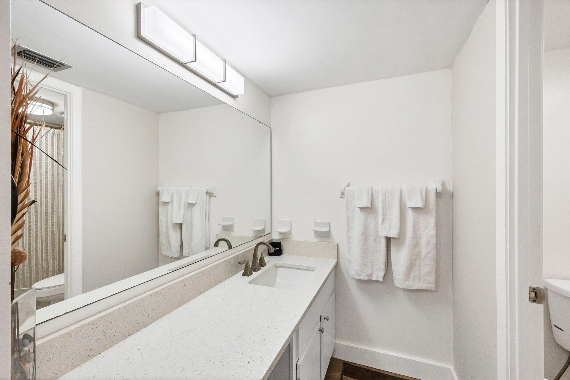 A modern bathroom with a white sink, mirror, and towel racks.