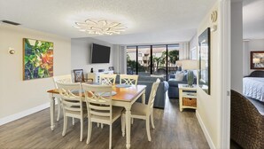 Ein geräumiges Wohnzimmer mit Esstisch und Stühlen, einer Couch und einem an der Wand befestigten Fernseher.