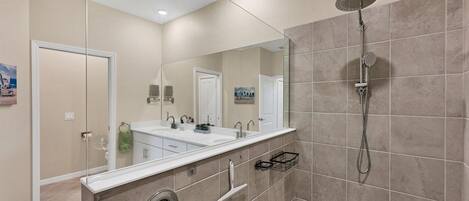 Un baño moderno con cabina de ducha, un espejo grande y un mueble de tocador doble.