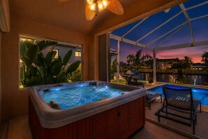 Un bain à remous avec vue sur une piscine et le coucher de soleil.