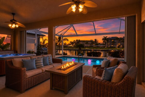 A poolside area with wicker furniture, a fire feature, and a view of a body of water and buildings at sunset. - Punta Gorda Isles 3 Bedroom Pool+Hot Tub Home 2 Home (Punta Gorda)