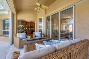 Patio soleggiato con mobili in vimini, un tavolo da pranzo e una ventola a soffitto.
