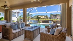 A sunlit patio with wicker furniture, a pool, and a view of a residential area. - Punta Gorda Isles 3 Bedroom Pool+Hot Tub Home 2 Home (Punta Gorda)