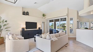 A modern living room with a sofa, two armchairs, a flat-screen TV, and a dining area with a kitchen counter. - Punta Gorda Isles 3 Bedroom Pool+Hot Tub Home 2 Home (Punta Gorda)