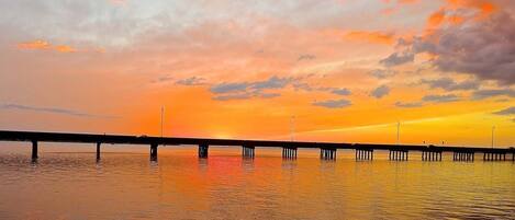 A pier extending into calm water during sunset with a clear sky.