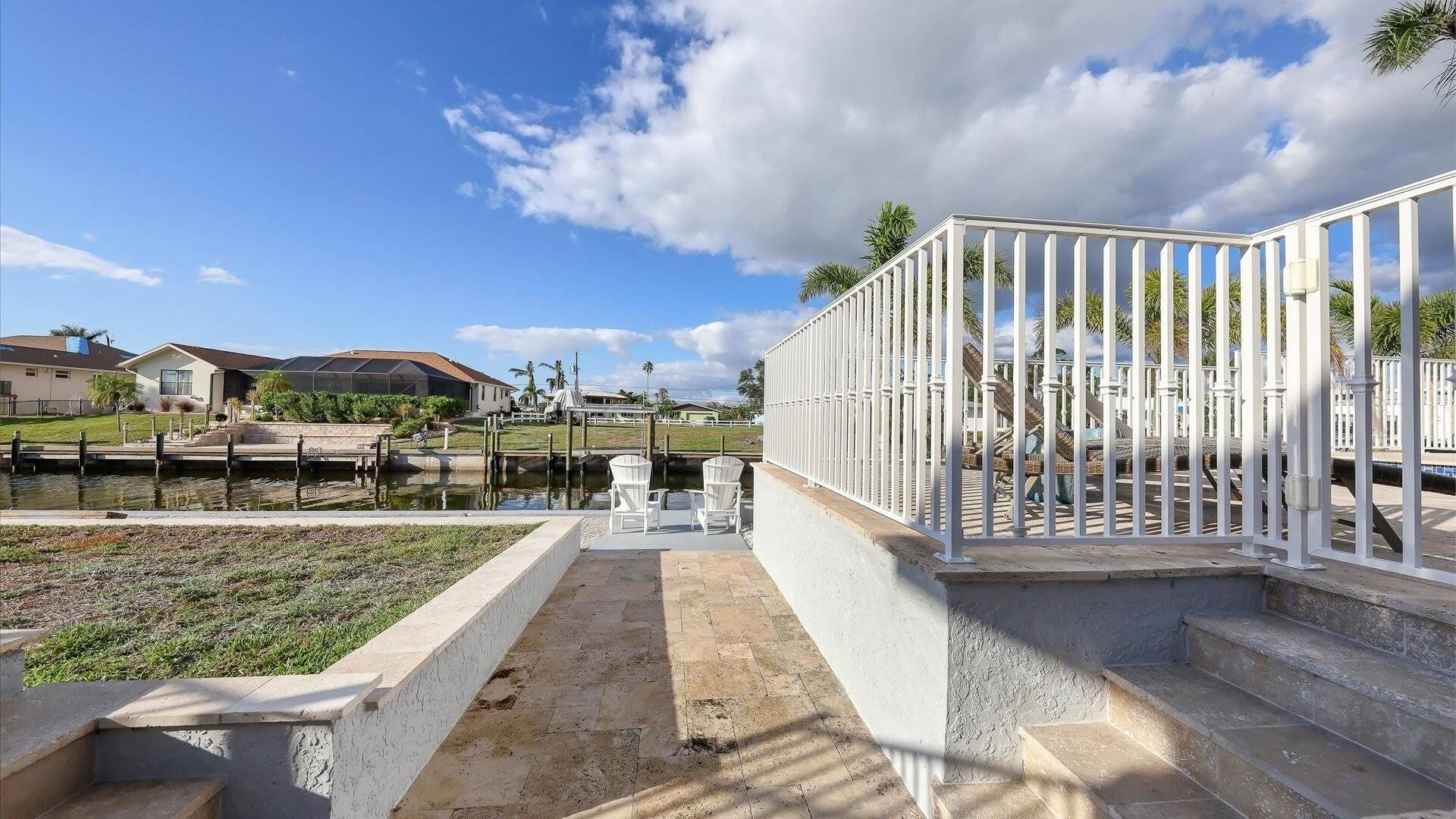 A waterfront property with a gated patio area, a small pool, and a view of the surrounding neighborhood.
