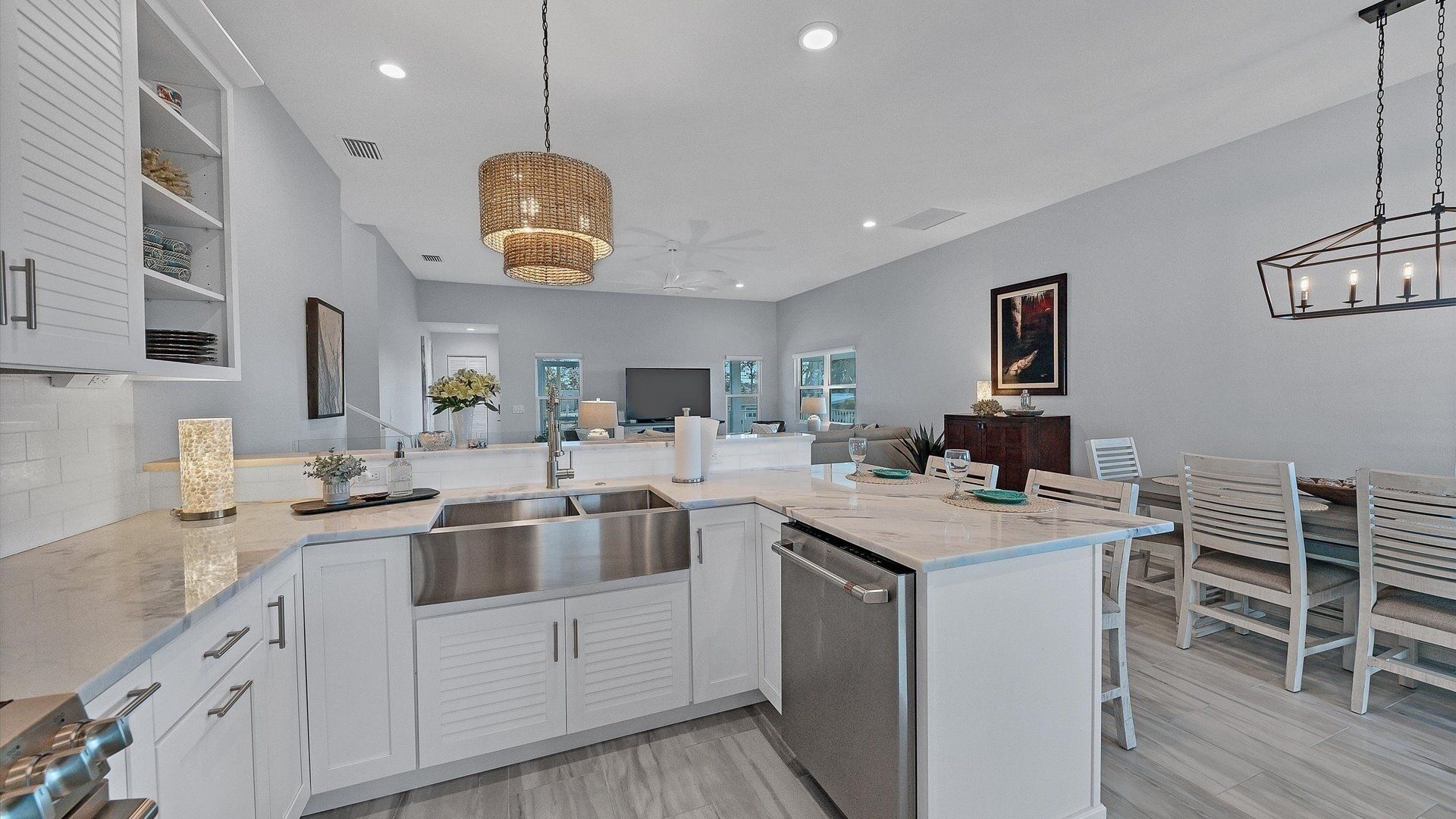 A modern kitchen with white cabinetry, a central island, stainless steel appliances, and a hanging light fixture.
