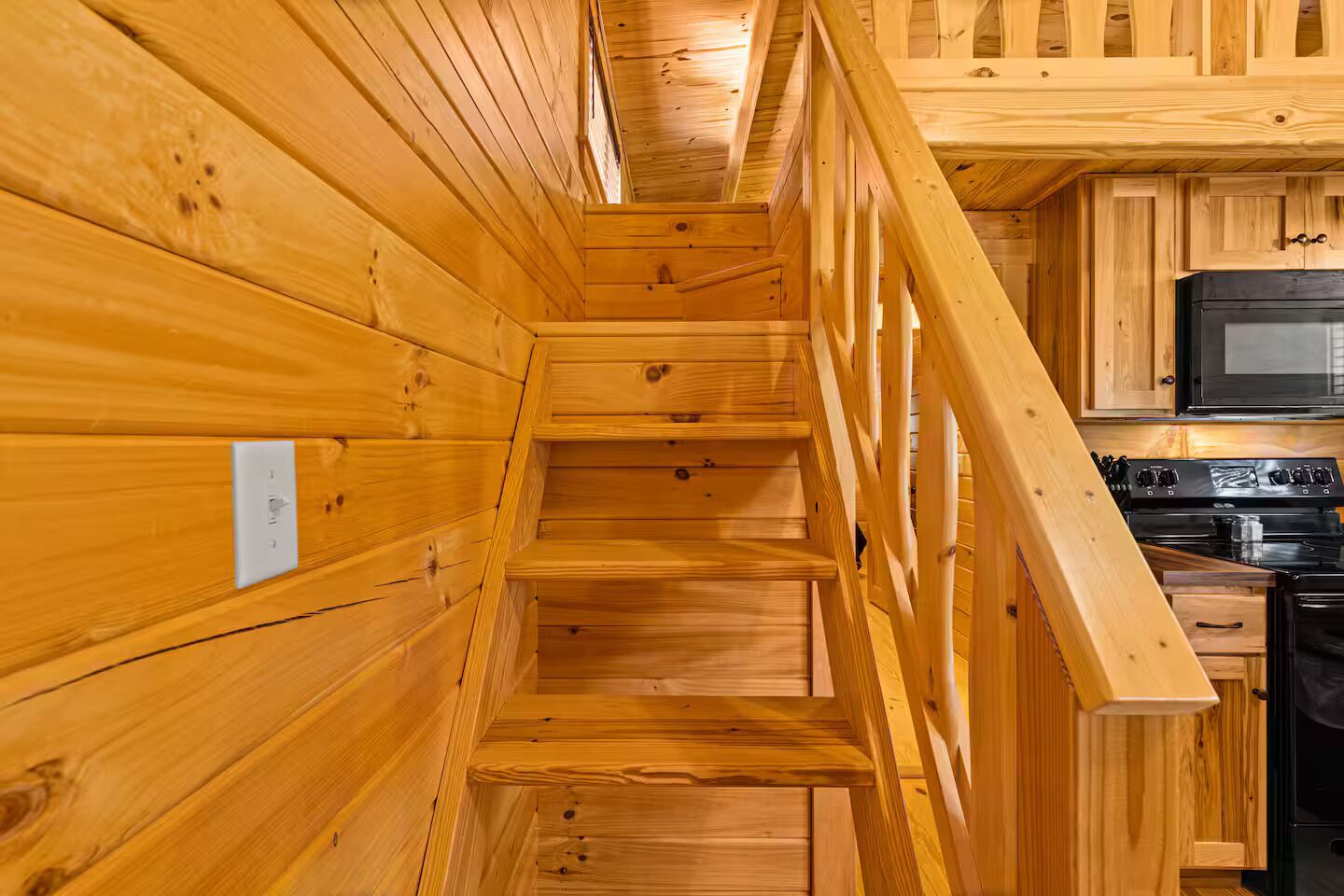 Interior de madera con una escalera que lleva a una zona de cocina.