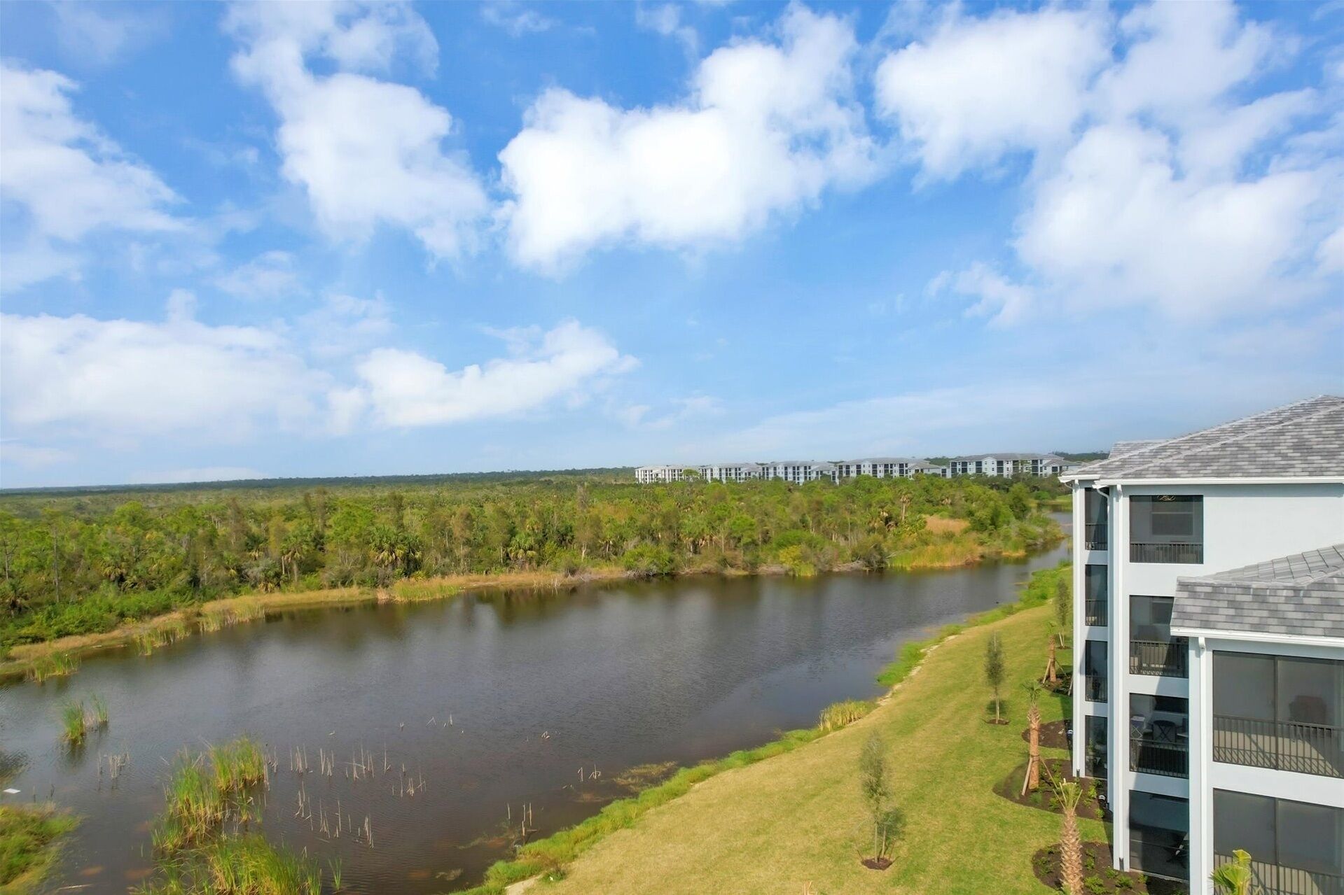 A modern building with a view of a lake and surrounding greenery.