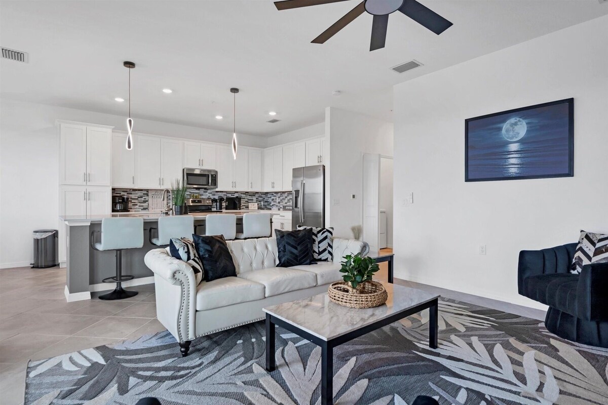 A modern living room with a sofa, coffee table, and a dining area with chairs.