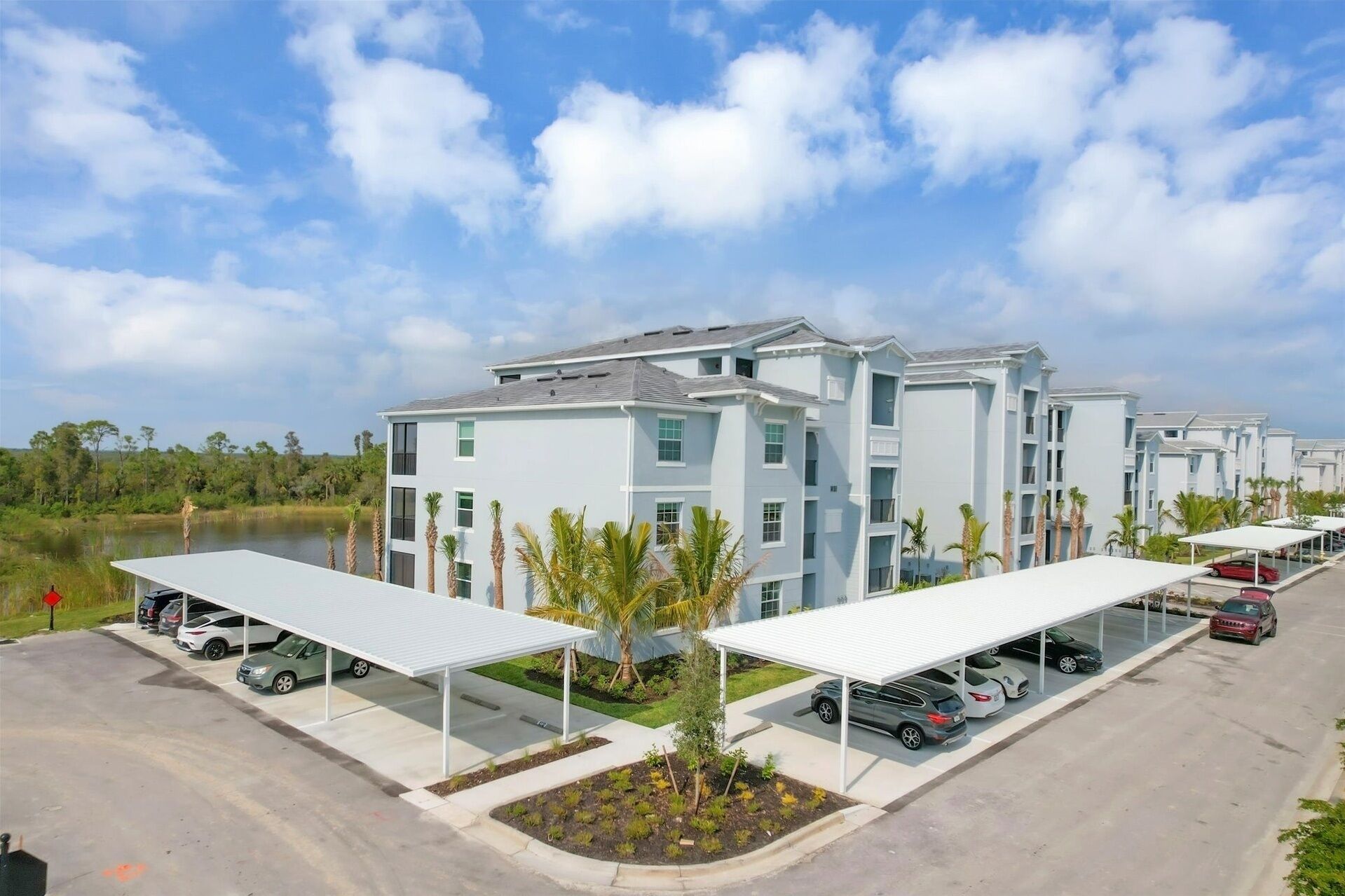 A modern multi-story hotel with a parking area and covered parking structures.