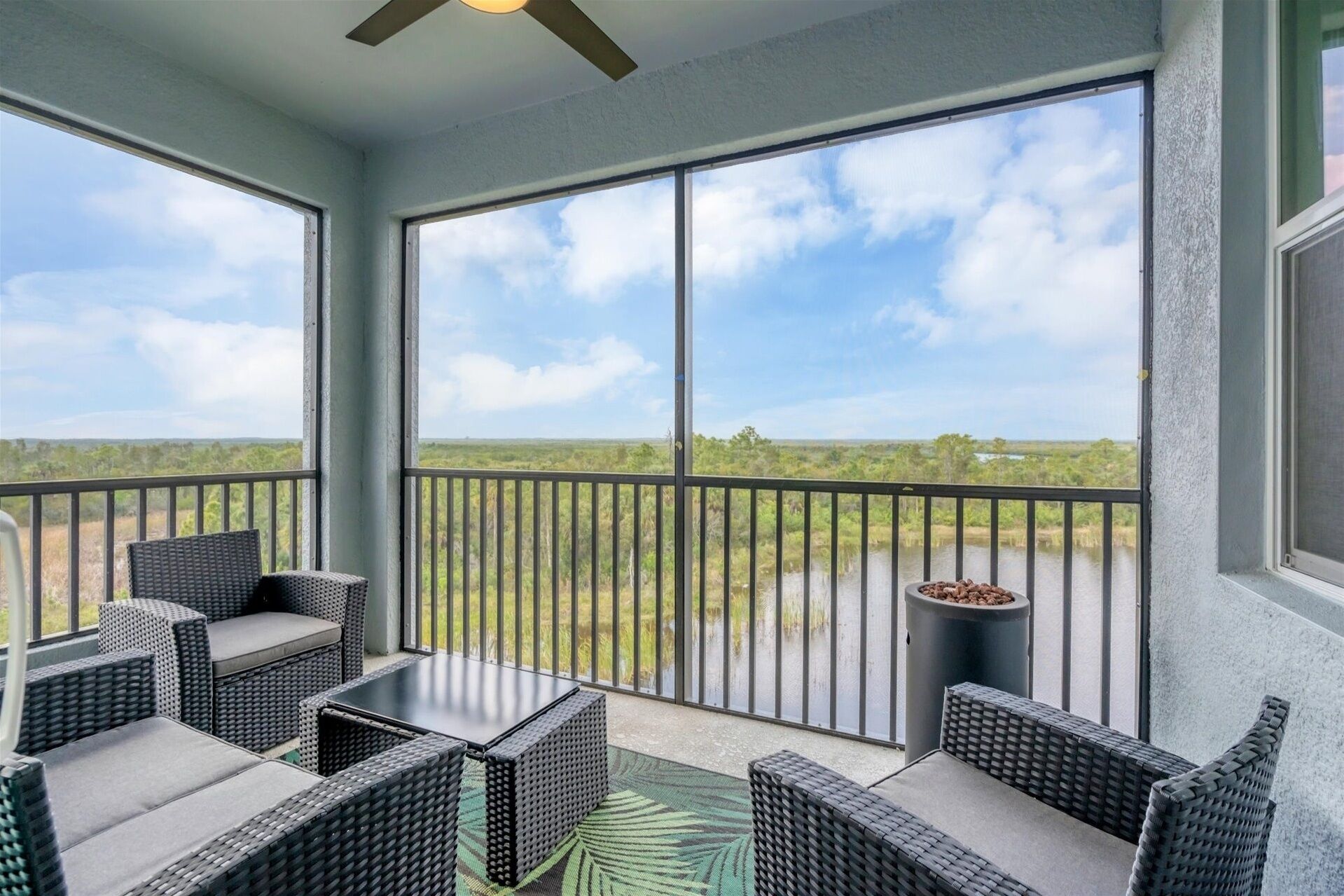 A balcony with wicker furniture and a view of a natural landscape.