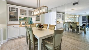 Een moderne keuken met witte kasten, een centraal eiland met zitplaatsen, en hanglampen.