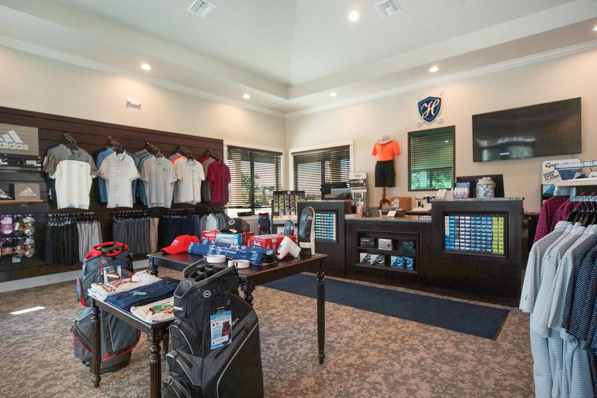 Un vestíbulo de hotel con una tienda de ropa, una recepción y una pantalla de televisión.