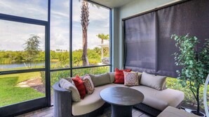 A sunroom with a large window overlooking a lake, a cushioned seating area, and a small table. - Heritage Landing 3br Condo - Golf Club Transfer Included! 3 Bedroom Condo (Punta Gorda)