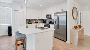 A modern kitchen with white cabinets, stainless steel appliances, a central island, and pendant lighting. - Heritage Landing 3br Condo - Golf Club Transfer Included! 3 Bedroom Condo (Punta Gorda)