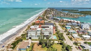 Vista aérea de un complejo turístico costero con propiedades frente a la playa, un puerto deportivo y aguas azul turquesa.