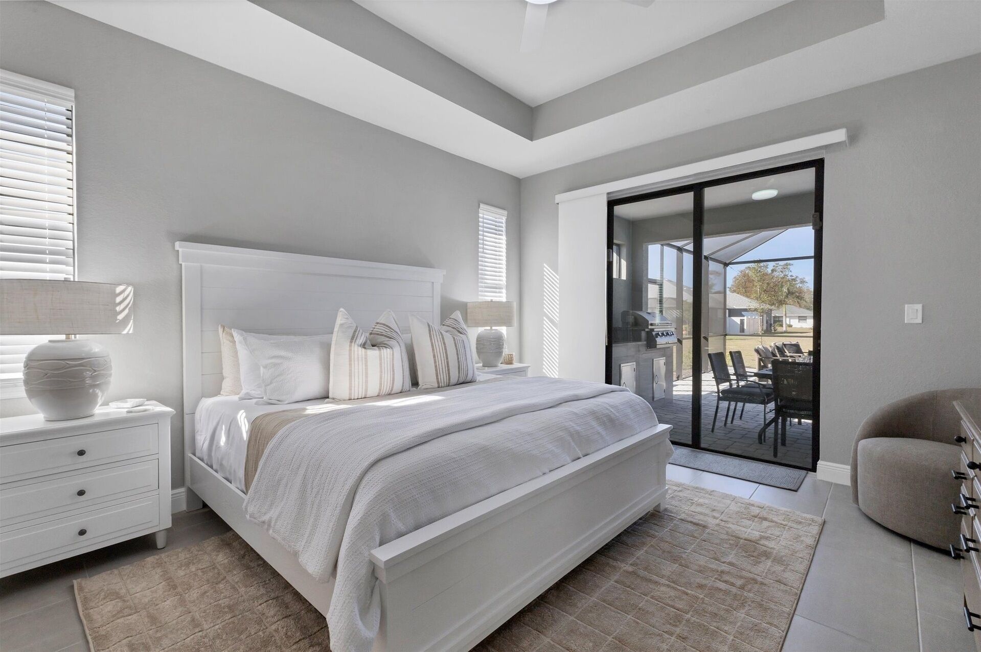 A bedroom with a large bed, a nightstand, a lamp, and a view of the outdoors through a sliding glass door.