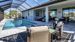 Uma área de piscina descoberta coberta, com espreguiçadeiras, uma mesa e um conjunto de jantar.