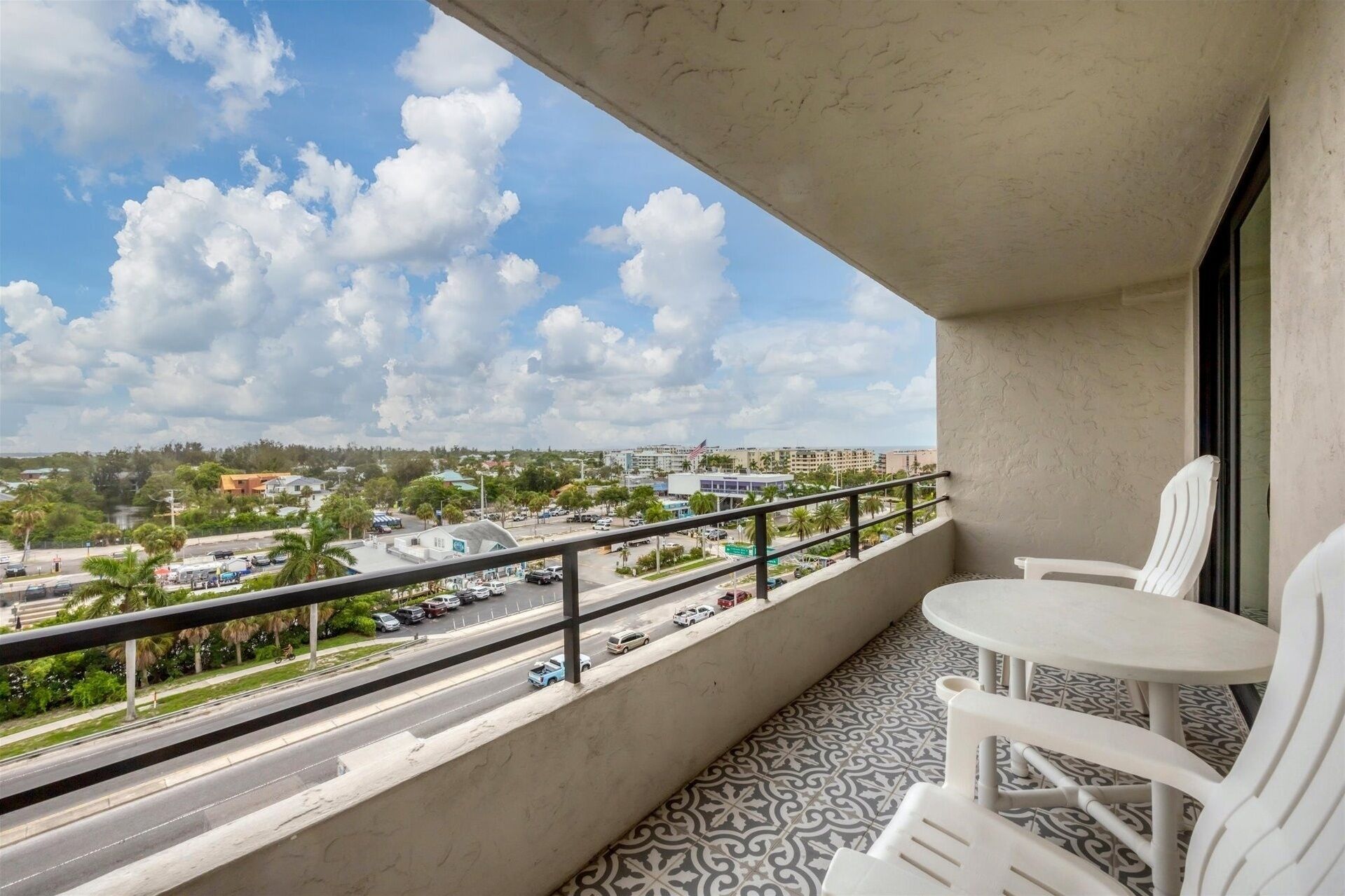 A balcony with a view of a cityscape, a table, and two chairs.