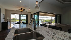 A modern kitchen with a large island, stainless steel sink, and a ceiling fan. - South Gulf Cove 3 Bedroom Canal Pool Home 3 Home (Port Charlotte)