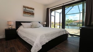 A bedroom with a large bed, two bedside tables with lamps, a window with curtains, and a motivational quote on the wall. - South Gulf Cove 3 Bedroom Canal Pool Home 3 Home (Port Charlotte)