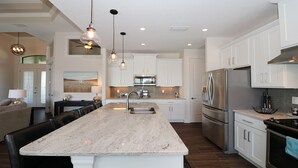 A modern kitchen with a large island, stainless steel appliances, and pendant lighting. - South Gulf Cove 3 Bedroom Canal Pool Home 3 Home (Port Charlotte)