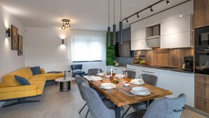 A modern living room with a yellow sofa, a dining table set for six, and a kitchen with white cabinets and a black countertop. - Villa Polaris by Villas Guide (Pula)