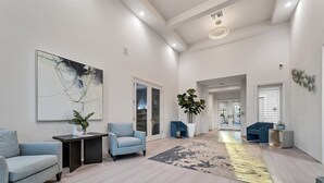 A spacious, modern living area with a large abstract painting, two blue armchairs, a coffee table, and a potted plant. - Heritage Landing Golf Club 3 Bedroom Condo 27 Night Minimum 3 Condo (Punta Gorda)