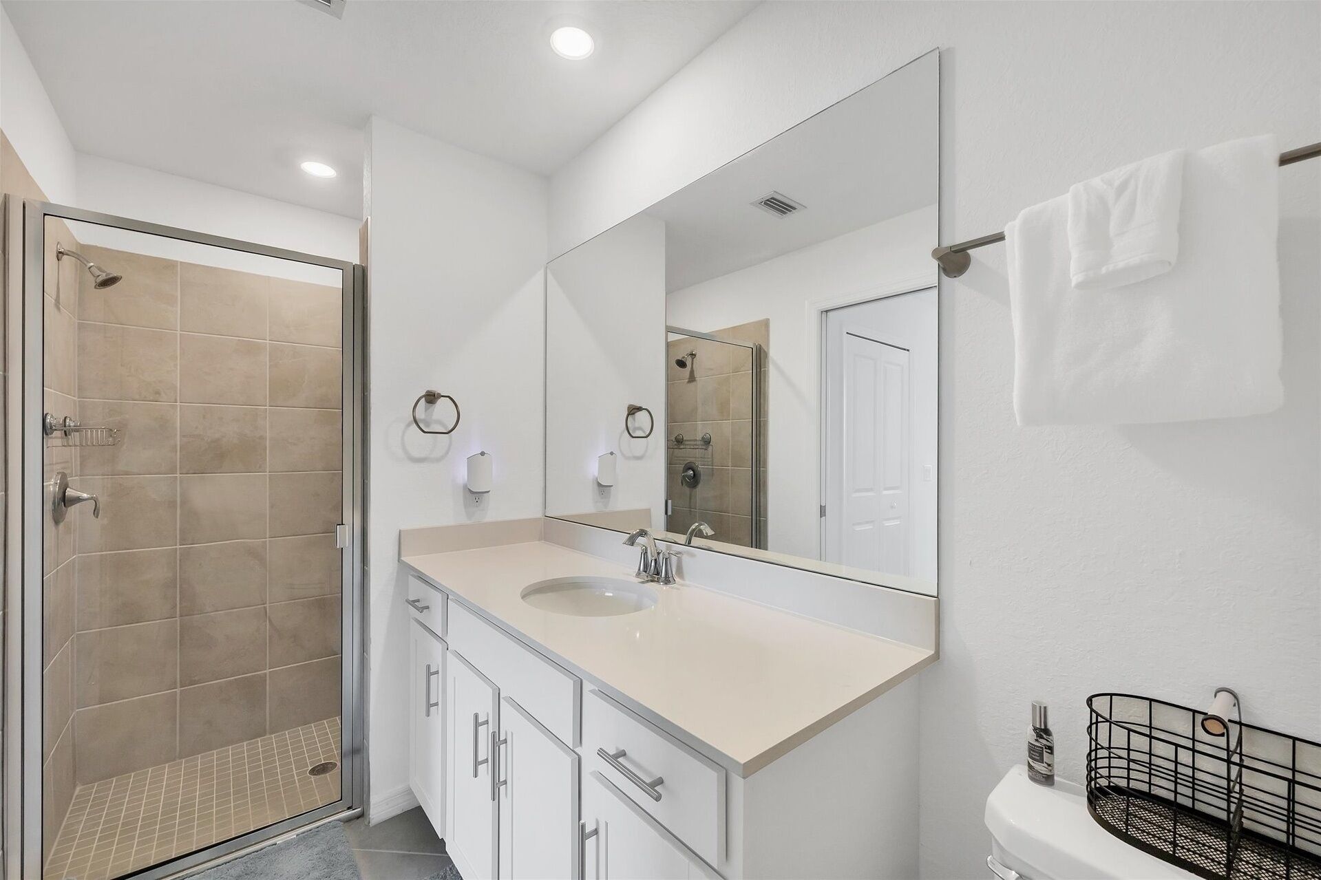 Un baño moderno con ducha, lavamanos con espejo y retrete.
