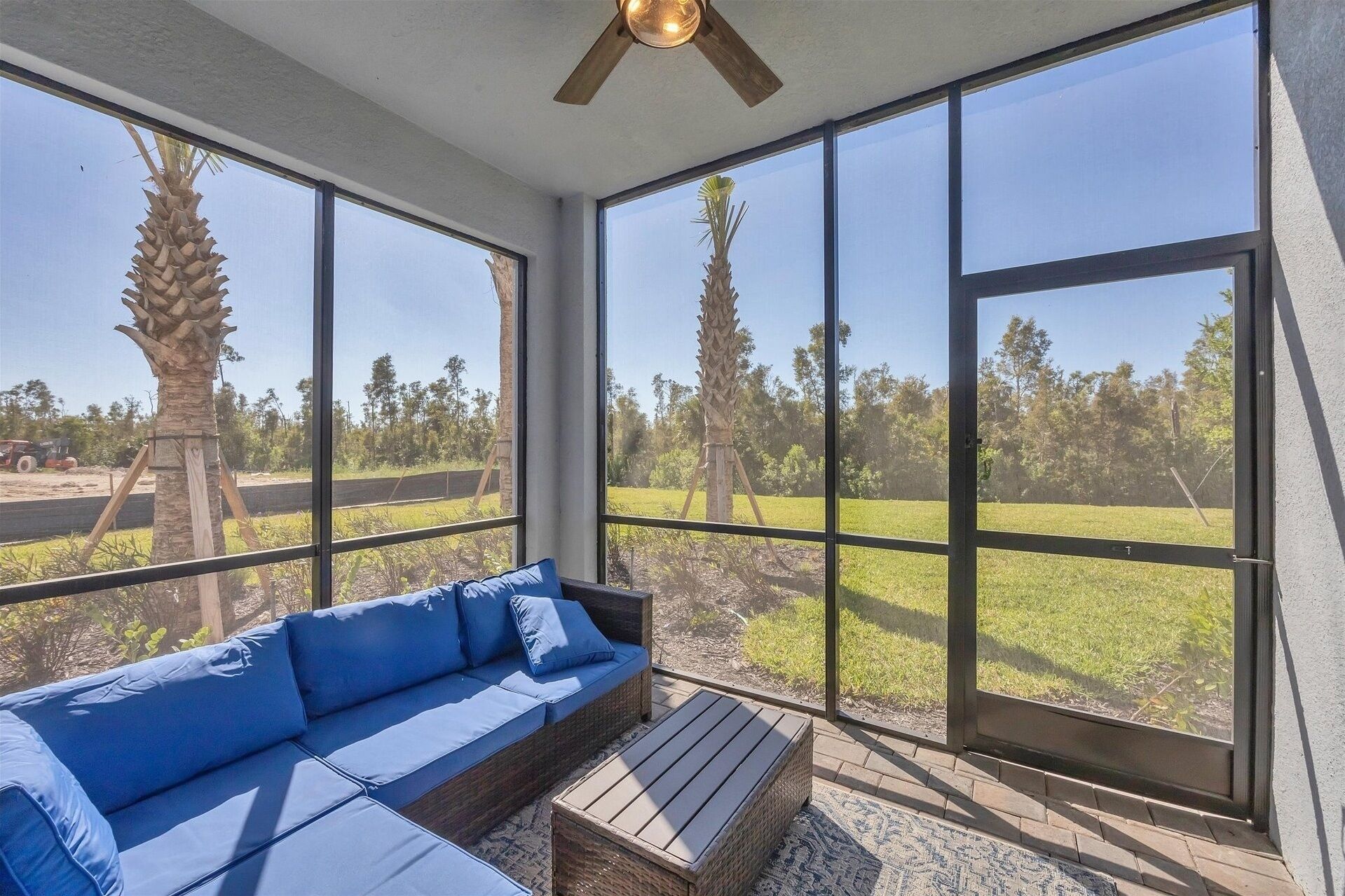 Un solárium con ventanas amplias, un ventilador de techo y un sofá azul.