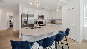 A modern kitchen with a central island, bar stools, stainless steel appliances, and pendant lighting. - Heritage Landing Golf Club 3 Bedroom Condo 27 Night Minimum 3 Condo (Punta Gorda)